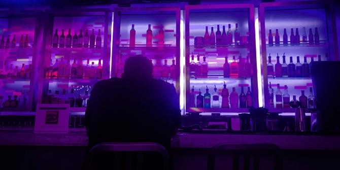 Photo from behind of a man sitting alone in a dark bar